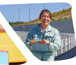 作業服を着た笑顔の女性が歩道に立っている写真